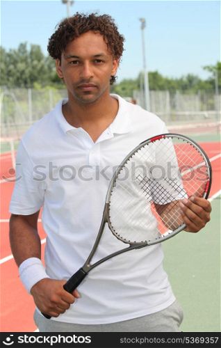 A tennis player holding his racket and looking at us.