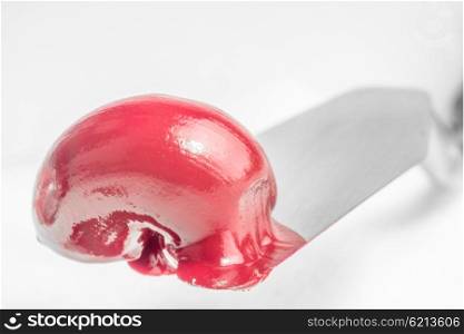 A thick squirt of red oil paint sits on the end of a paint knife, on a white background.