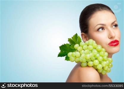 A thoughtful sexy lady with a bunch of healthy green grapes on her shoulder looking aside.