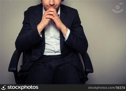 A thoughtful young businessman is sitting in an office chair