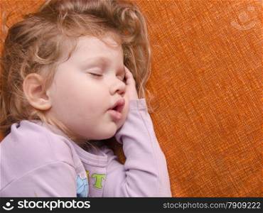 A three year old girl sleeping on the couch, placing a hand under his head