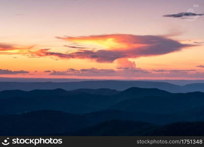 A thunderstorm dissipating off in the distance as the setting sun lights the anvil cloud tops on fire over Shenandoah National Park, Virginia