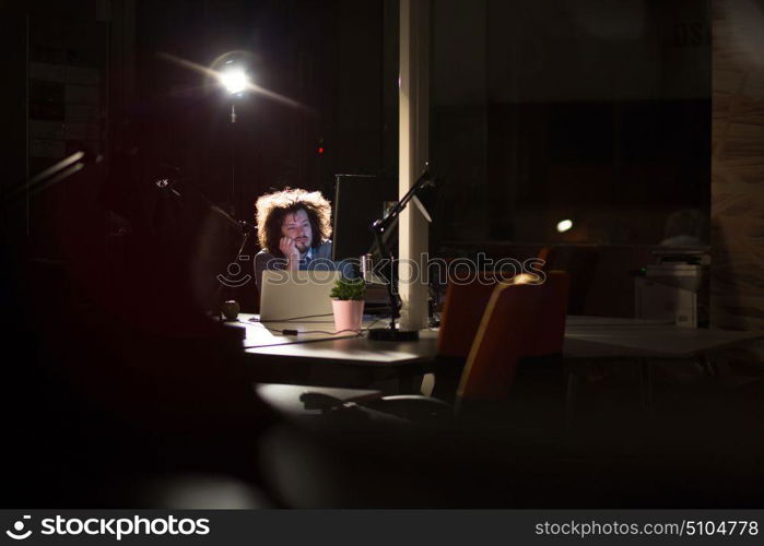 A time for relax. Young tired casual businessman relaxing at the desk in his night office