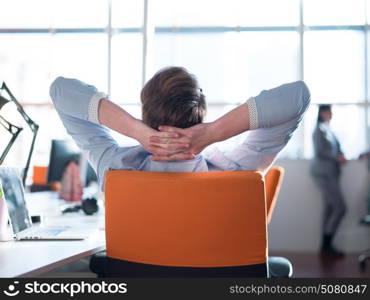 A time for relax. Young tired casual businessman relaxing at the desk in his office