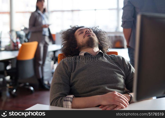 A time for relax. Young tired casual businessman relaxing at the desk in his office