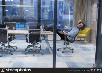 A time for relax. Young tired casual businessman relaxing at the desk in his office