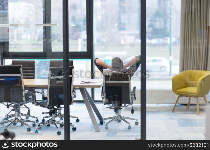 A time for relax. Young tired casual businessman relaxing at the desk in his office