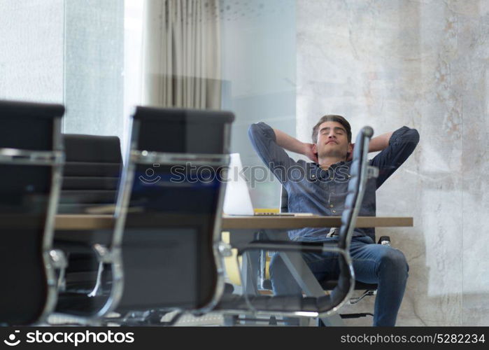 A time for relax. Young tired casual businessman relaxing at the desk in his office