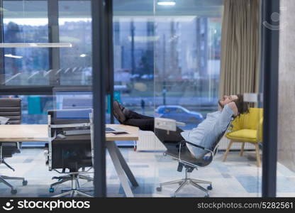 A time for relax. Young tired casual businessman relaxing at the desk in his office