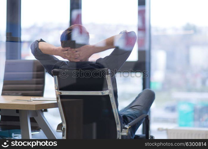 A time for relax. Young tired casual businessman relaxing at the desk in his office