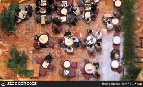 A time lapse shot and a real time shot, of a busy indoor cafe from a high angle