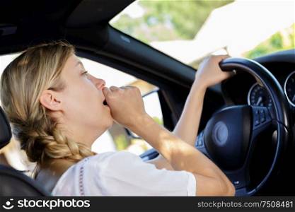 a tired female driver yawning