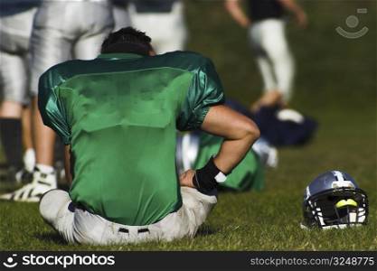 A tired football player is taking rest after the game.