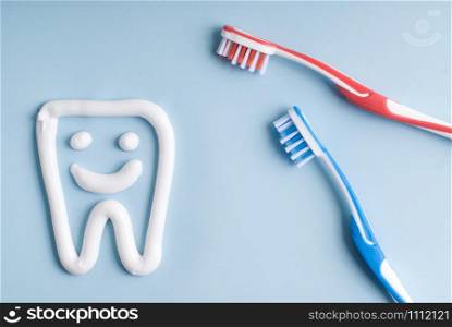 A tooth with a smiling face with toothbrushes on blue background.