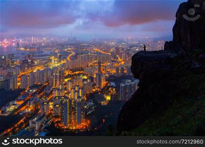 A tourist man standing on Suicide cliff in Hong Kong Downtown, China. Financial district and business centers in technology smart city in Asia. Skyscraper and high-rise buildings at night.