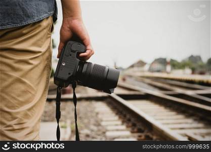 A tourist man standing with a digital camera near the railroad tracks, ideas about tourism and traveling.