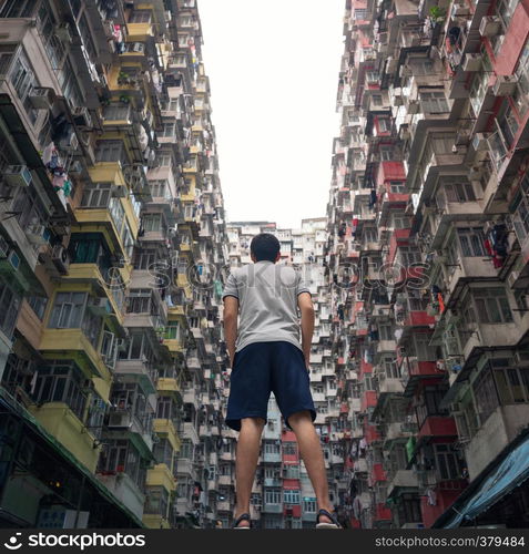 A tourist man with Yick Fat Building in travel Hong Kong concept, Quarry Bay. Residential area in old apartment. High-rise building, skyscraper with windows of architecture in urban city.