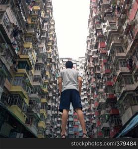A tourist man with Yick Fat Building in travel Hong Kong concept, Quarry Bay. Residential area in old apartment. High-rise building, skyscraper with windows of architecture in urban city.