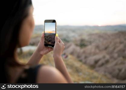 a tourist takes pictures of the sunset in the mountains on a mobile phone