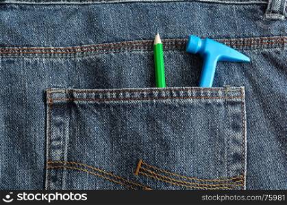 A toy plastic hammer in a back pocket of a denim with a pencil