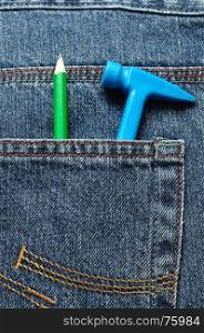 A toy plastic hammer in a back pocket of a denim with a pencil