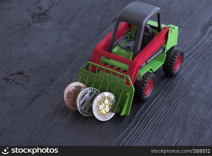 A toy tractor rakes coins of crypto currency on a black wooden background: bitcoin, lightcoin, ripple. The concept of the game with crypto-currencies.. Toy tractor rakes coins crypto currency