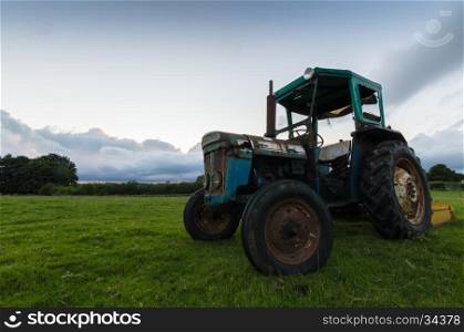 A tractor in a field at sunset, in the countrside in the Peak District