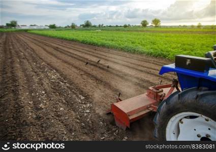 A tractor with a milling machine is cultivating a farm field. Loose crushed moist soil after cultivating with a cultivator. Loosening surface, land cultivation. Farming. Use agricultural machinery