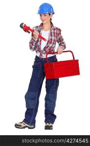 A tradeswoman holding a pipe wrench and toolbox