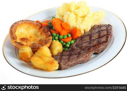 A traditional pub-grub style British meal of rump steak, mixed veg, mashed and roasted potatoes and yorkshire pudding, isolated over white