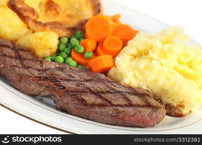 A traditional pub-grub style British meal of rump steak, mixed veg, mashed and roasted potatoes and