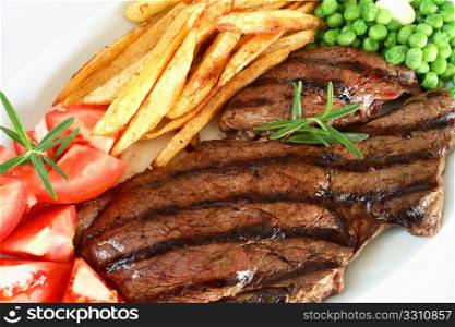 A traditional steak grill, with rump steak, french fried potato chips,tomato and peas, garnished with a sprig of rosemary