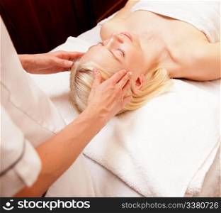 A tranquil woman receiving a head massage at a spa