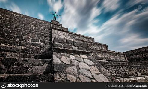 A traveler standing on the top of the Teotihuacan pyramid. Time-lapse sky shows the concept of centuries passing this tremendous ancient structure.