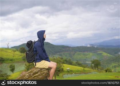 A traveling man enjoying and relaxing over beautiful green mountain view in rain season, Tropical climate.