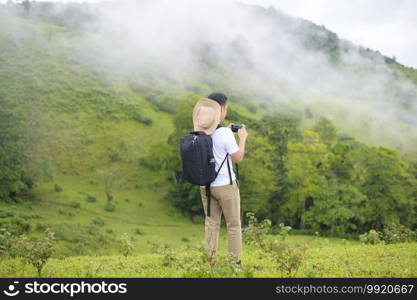 A traveling man enjoying and relaxing over beautiful green mountain view in rain season, Tropical climate.