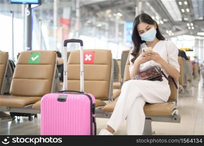A traveller woman is wearing protective mask in International airport, travel under Covid-19 pandemic, safety travels, social distancing protocol, New normal travel concept .. A traveller woman is wearing protective mask in International airport, travel under Covid-19 pandemic, safety travels, social distancing protocol, New normal travel concept