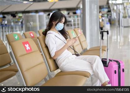A traveller woman is wearing protective mask in International airport, travel under Covid-19 pandemic, safety travels, social distancing protocol, New normal travel concept .. A traveller woman is wearing protective mask in International airport, travel under Covid-19 pandemic, safety travels, social distancing protocol, New normal travel concept