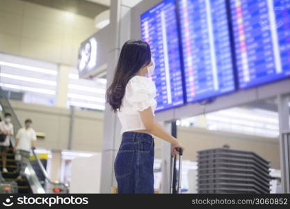 A traveller woman is wearing protective mask in International airport, travel under Covid-19 pandemic, safety travels, social distancing protocol, New normal travel concept