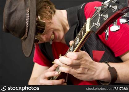 A trendy looking guitar player during a heavy guitar solo. Selective focus on the musicians left hand