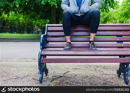 A trendy young woman is sitting on a park bench