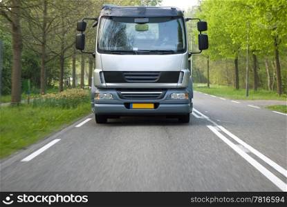A truck driving along a country road towards the camera