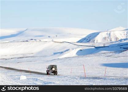 A truck driving on a barren landscape of snow and ice - Svalbard, Norway