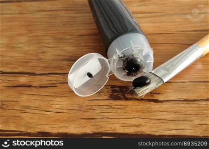 A tube of black paint with a paint brush