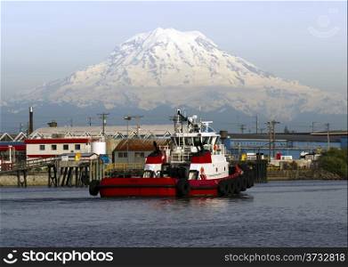 A Tugboat returns to dock after guiding a container ship out to sea Mt. Rainier in background