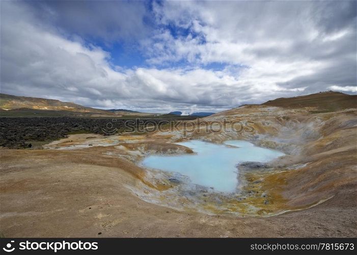 A turquoise lake in a caldera of the Krafla volcanic system, with the lava fields and geothermal activity and its mudpools in the Myvatn region, Iceland