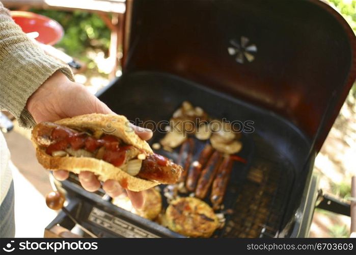 A typical Australian Barber Que. Putting sauce onto a Sausage. Melbourne Australia.