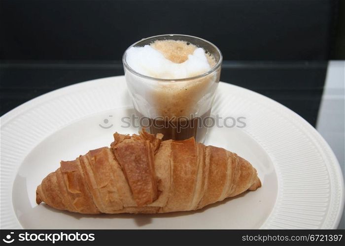 A typical French breakfast: a croissant and an espresso coffee with milk