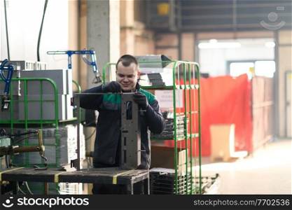 a uniformed worker working in a modern metal production and processing factory assembles parts of a new machine on his desk. High quality photo. a uniformed worker working in a modern metal production and processing factory assembles parts of a new machine on his desk