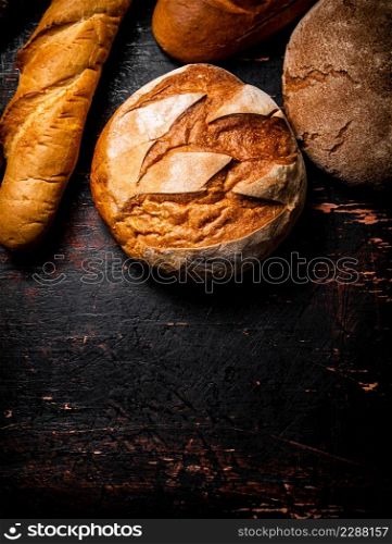A variety of delicious bread on the table. Against a dark background. High quality photo. A variety of delicious bread on the table.